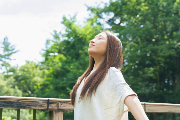 森林の中で深呼吸している女性